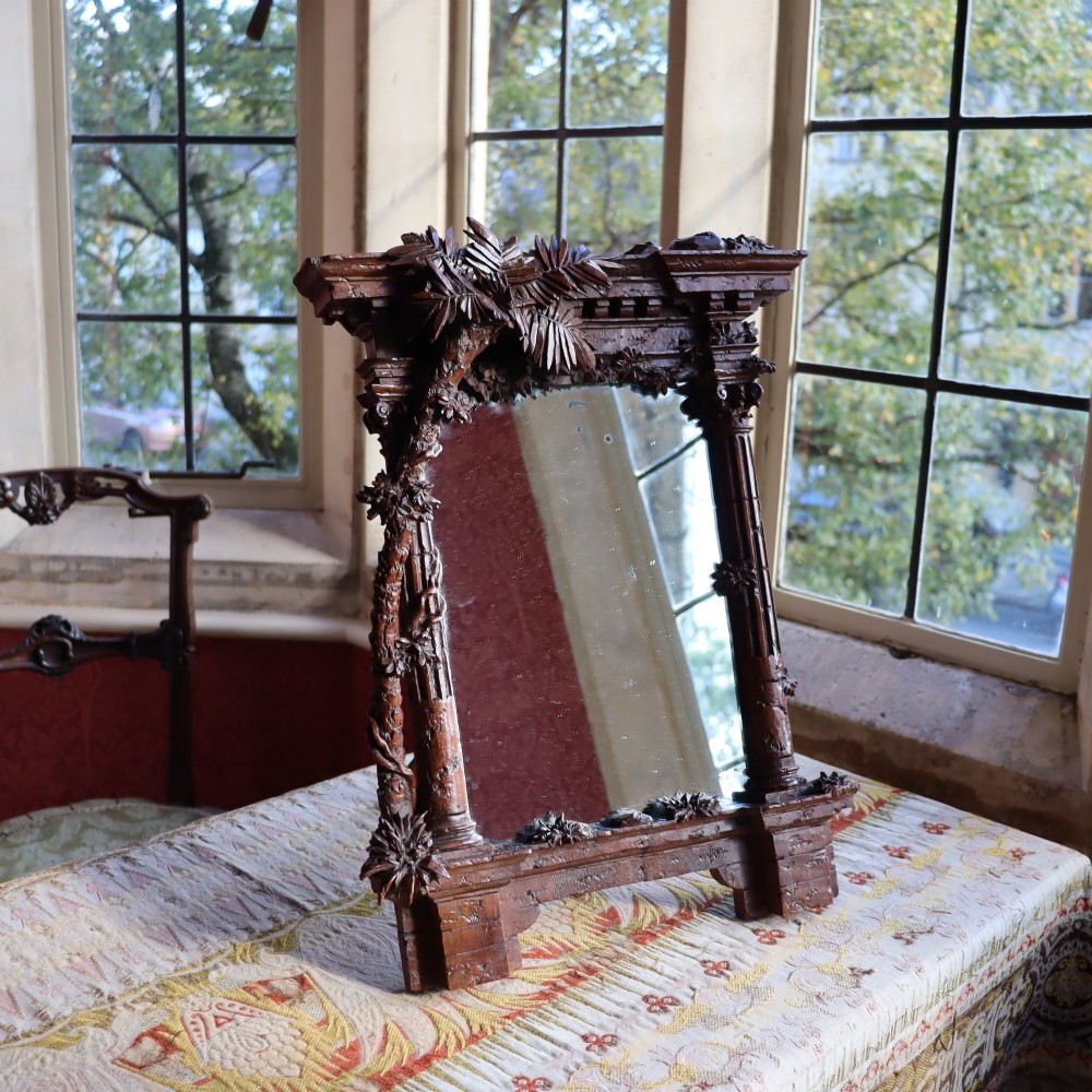 A late nineteenth-century Black Forest carved walnut table mirror featuring ornate architectural columns and botanical leaf carvings around the central rectangular mirror glass.