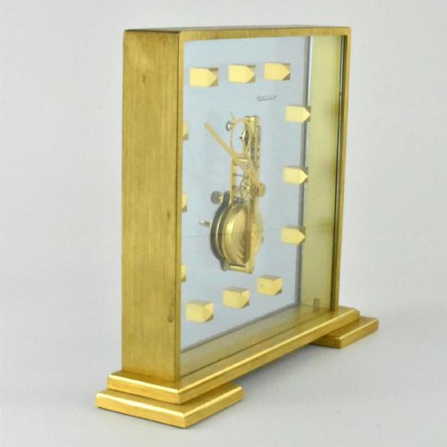 fig 1. A mid-century Jaeger-LeCoultre brass and glass square mantel clock featuring a visible internal skeleton movement and square brass hour markers.