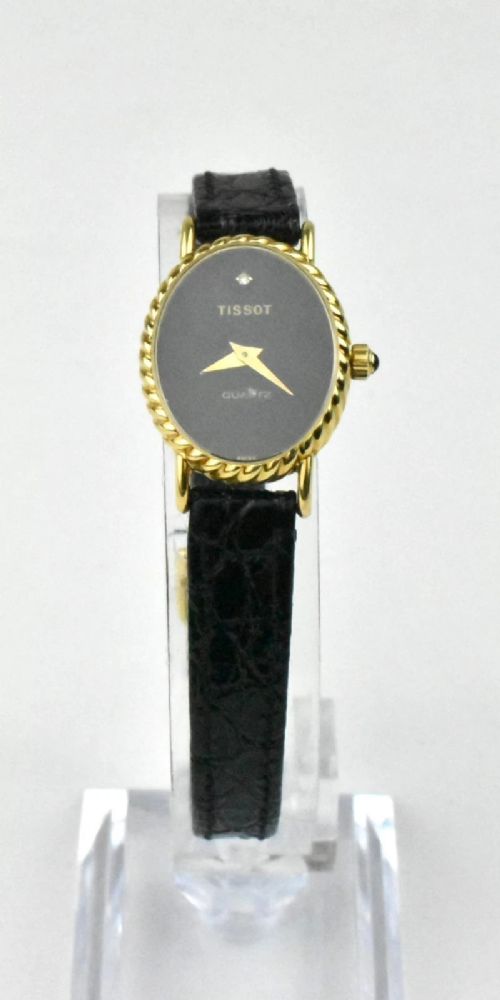 fig 1. A vintage Tissot ladies wristwatch featuring an oval 18ct gold rope-twist bezel, a black dial with a single diamond marker at twelve oclock, and a black leather strap.