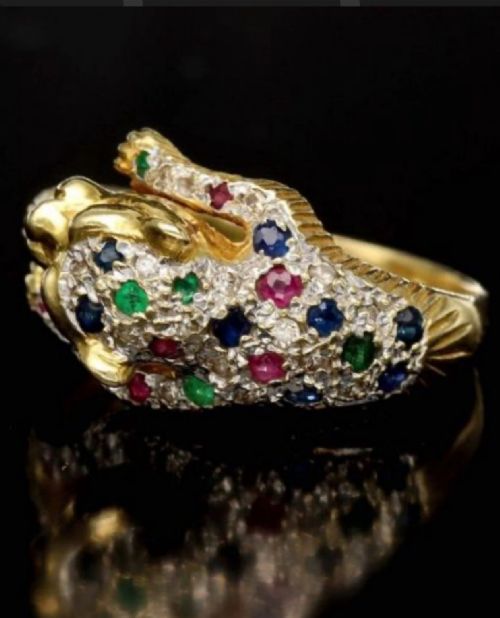 fig 1. A profile view of an 18ct yellow gold ring sculpted into a panther head featuring ruby eyes and pave-set gemstones along the band.