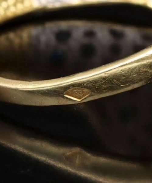 fig 3. A profile view of an 18ct yellow gold ring sculpted into a panther head featuring ruby eyes and pave-set gemstones along the band.