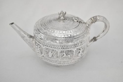 fig 1. A three-piece Victorian sterling silver tea set decorated with chased Indianesque zodiac panels, featuring a teapot, sugar bowl, and cream jug.