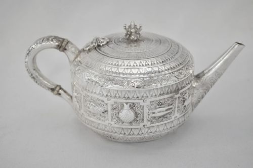 fig 2. A three-piece Victorian sterling silver tea set decorated with chased Indianesque zodiac panels, featuring a teapot, sugar bowl, and cream jug.