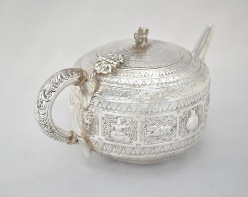 fig 3. A three-piece Victorian sterling silver tea set decorated with chased Indianesque zodiac panels, featuring a teapot, sugar bowl, and cream jug.