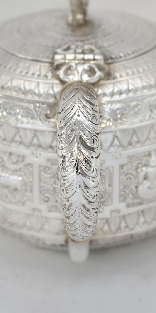 fig 4. A three-piece Victorian sterling silver tea set decorated with chased Indianesque zodiac panels, featuring a teapot, sugar bowl, and cream jug.