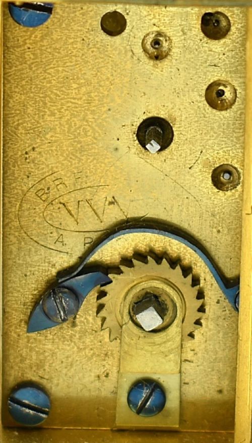 fig 3. A miniature French gilt brass carriage clock with ornate scroll engraving and a white enamel dial, shown inside its open leather travelling case.
