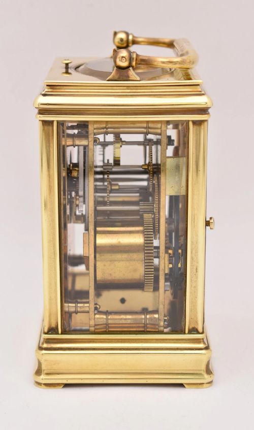 A late nineteenth-century French brass gorge case carriage clock featuring a white enamel dial with Roman numerals and a hinged top carrying handle. View V