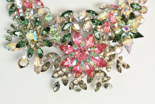 fig 2. A 1950s Christian Dior costume jewellery parure set featuring a necklace, brooch, and clip-on earrings with pink, green, and aurora borealis crystal floral clusters.