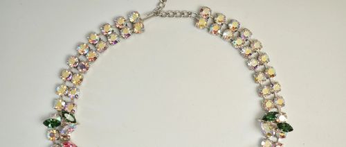 fig 3. A 1950s Christian Dior costume jewellery parure set featuring a necklace, brooch, and clip-on earrings with pink, green, and aurora borealis crystal floral clusters.