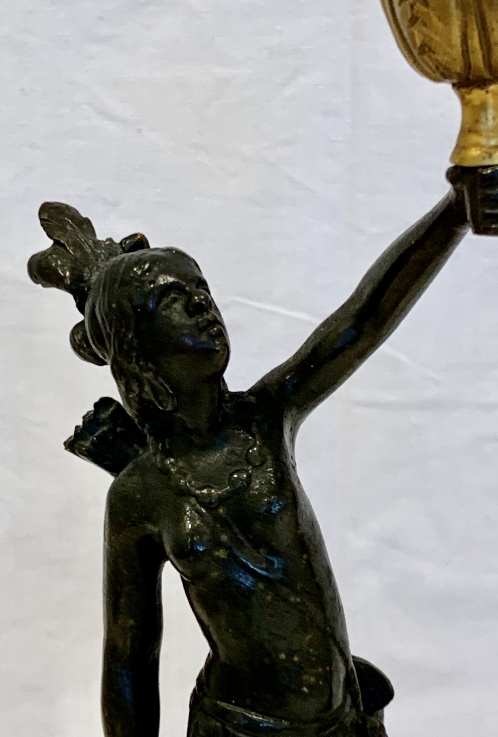 A pair of dark patinated metal figural candlesticks featuring standing figures holding gilded tulip-shaped candle sockets aloft on ornate gilded scrollwork bases. View IX