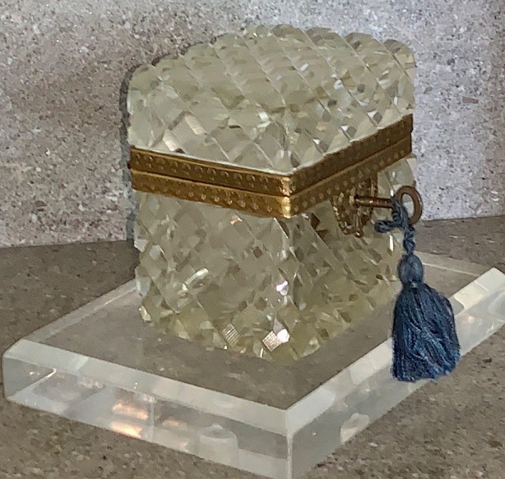A square diamond-cut clear glass casket box featuring a hinged gilt-bronze rim with an ornate metal clasp. View III