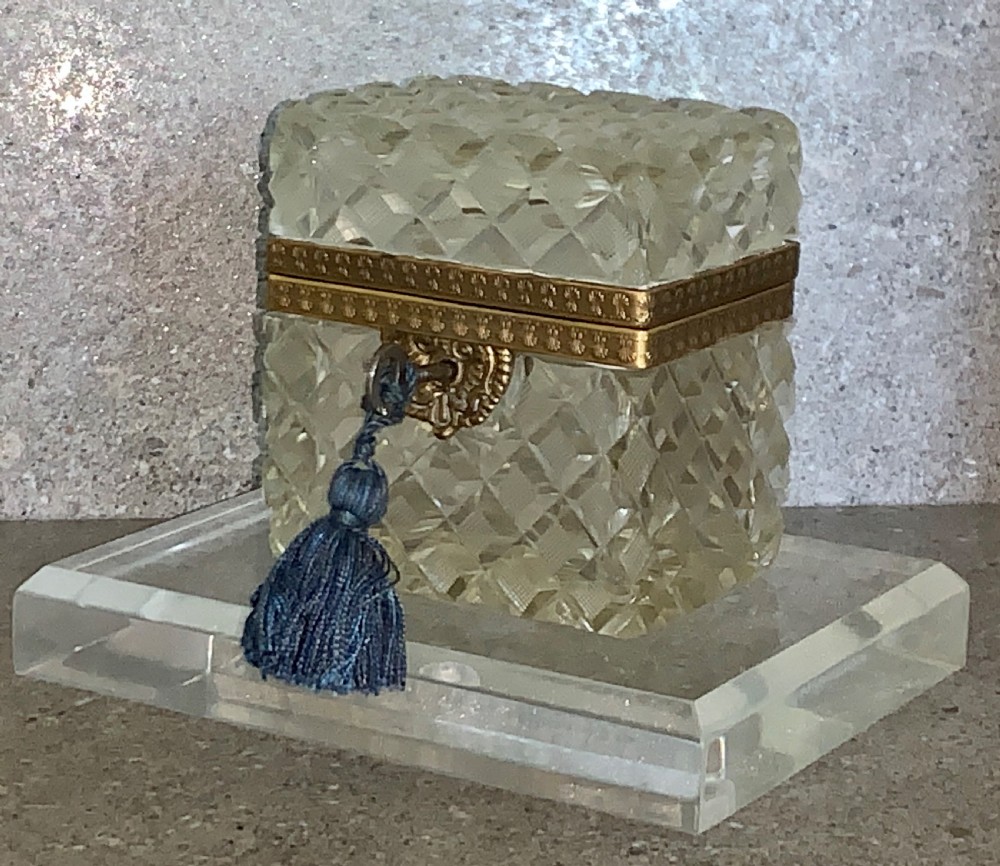 A square diamond-cut clear glass casket box featuring a hinged gilt-bronze rim with an ornate metal clasp. View IV
