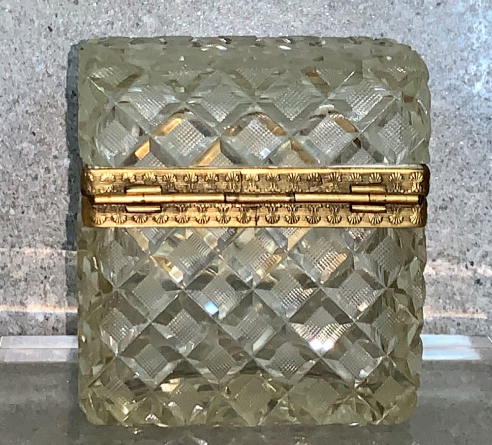 A square diamond-cut clear glass casket box featuring a hinged gilt-bronze rim with an ornate metal clasp. View IX