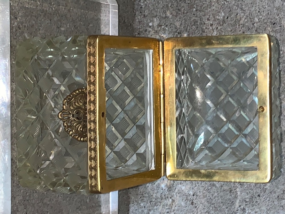 A square diamond-cut clear glass casket box featuring a hinged gilt-bronze rim with an ornate metal clasp. View XI