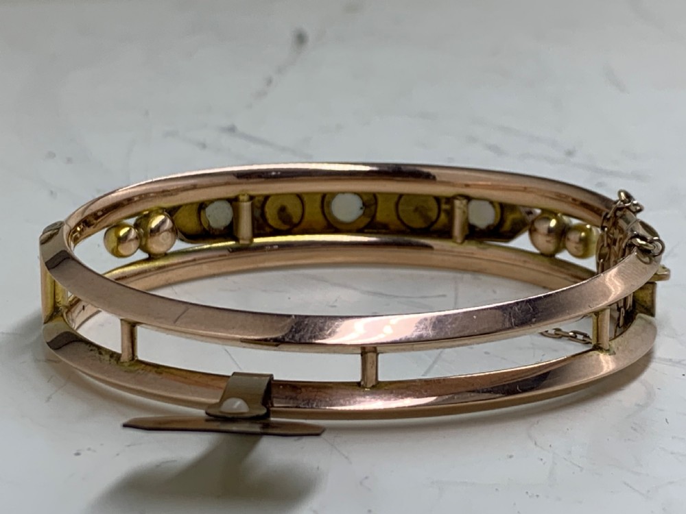 A Victorian 9ct rose gold hinged bangle with star-set diamonds and cabochon opals arranged on a central tapered panel. View V