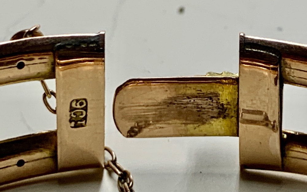A Victorian 9ct rose gold hinged bangle with star-set diamonds and cabochon opals arranged on a central tapered panel. View VI