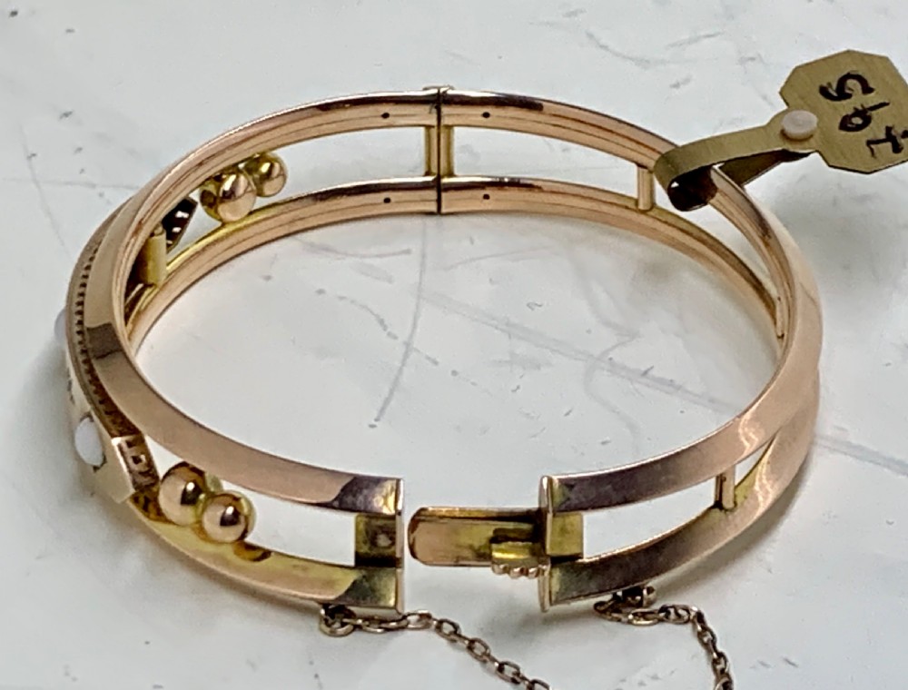 A Victorian 9ct rose gold hinged bangle with star-set diamonds and cabochon opals arranged on a central tapered panel. View VII