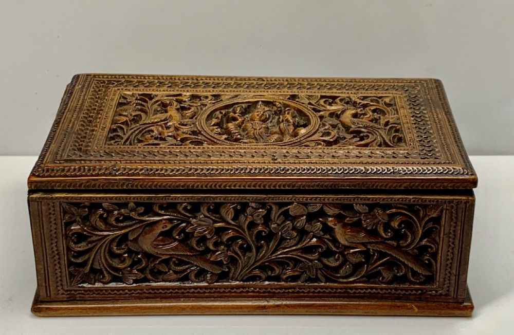 A nineteenth-century rectangular wooden box featuring intricate high-relief carvings of birds, foliage, and a central circular motif across the lid and sides. View II