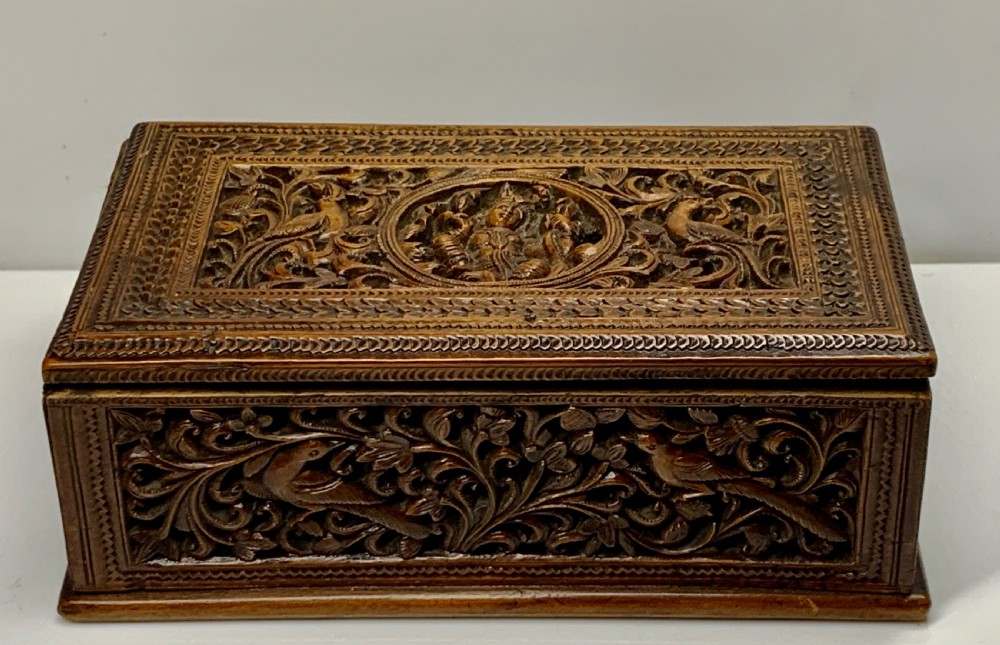 A nineteenth-century rectangular wooden box featuring intricate high-relief carvings of birds, foliage, and a central circular motif across the lid and sides.