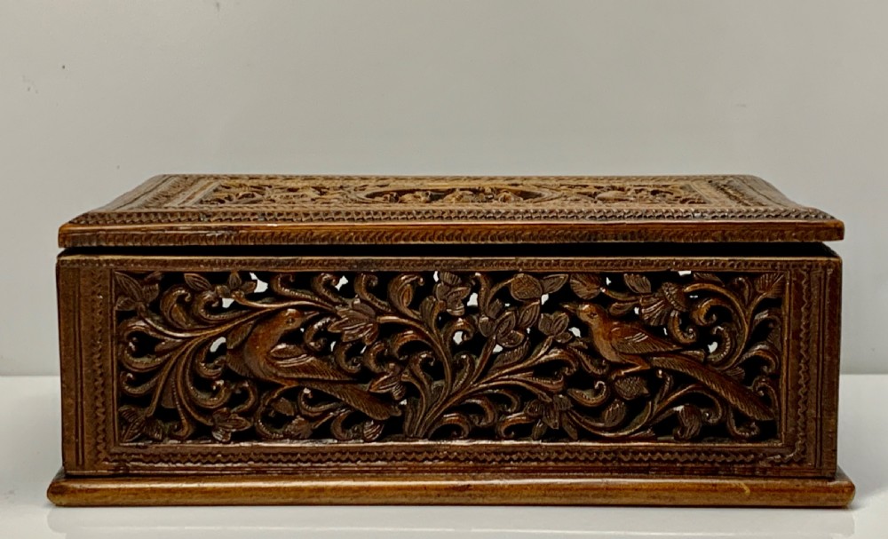 A nineteenth-century rectangular wooden box featuring intricate high-relief carvings of birds, foliage, and a central circular motif across the lid and sides. View III