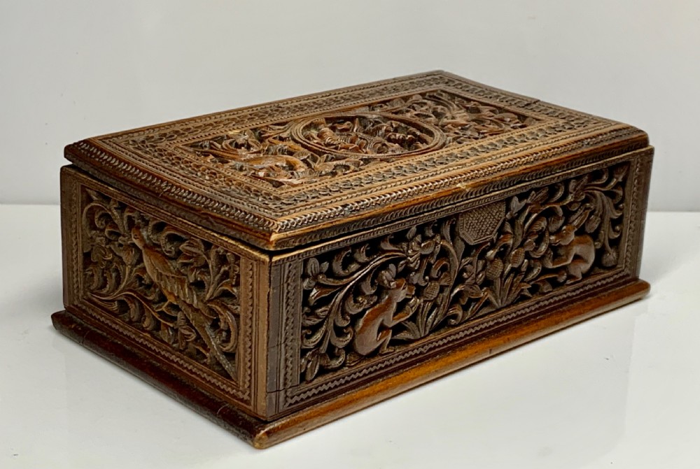 A nineteenth-century rectangular wooden box featuring intricate high-relief carvings of birds, foliage, and a central circular motif across the lid and sides. View V