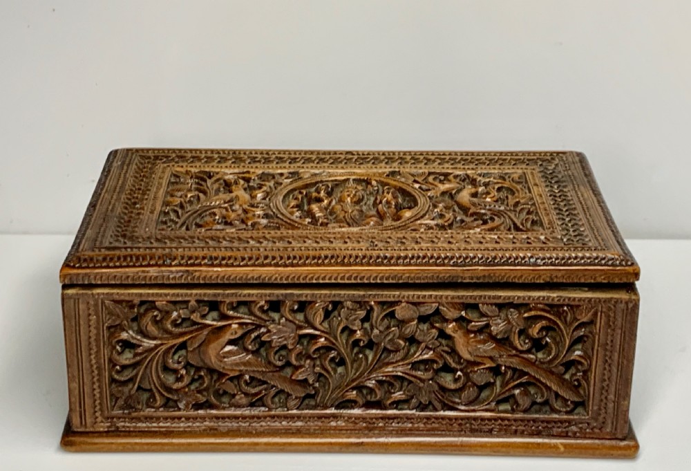 A nineteenth-century rectangular wooden box featuring intricate high-relief carvings of birds, foliage, and a central circular motif across the lid and sides. View IX
