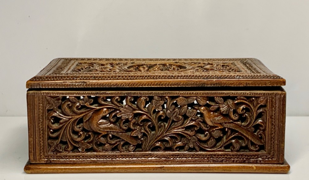 A nineteenth-century rectangular wooden box featuring intricate high-relief carvings of birds, foliage, and a central circular motif across the lid and sides. View X