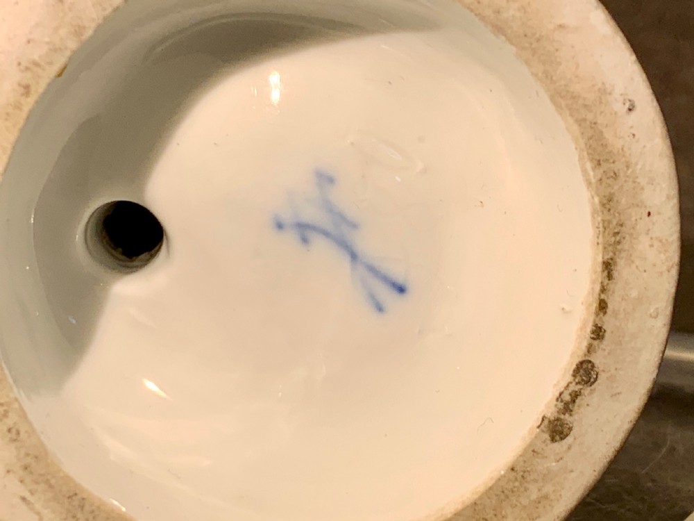 A polychrome porcelain figurine depicting a woman leaning against a barrel with a pitcher and funnel, set on a circular base with gilt Greek key ornamentation. View VIII
