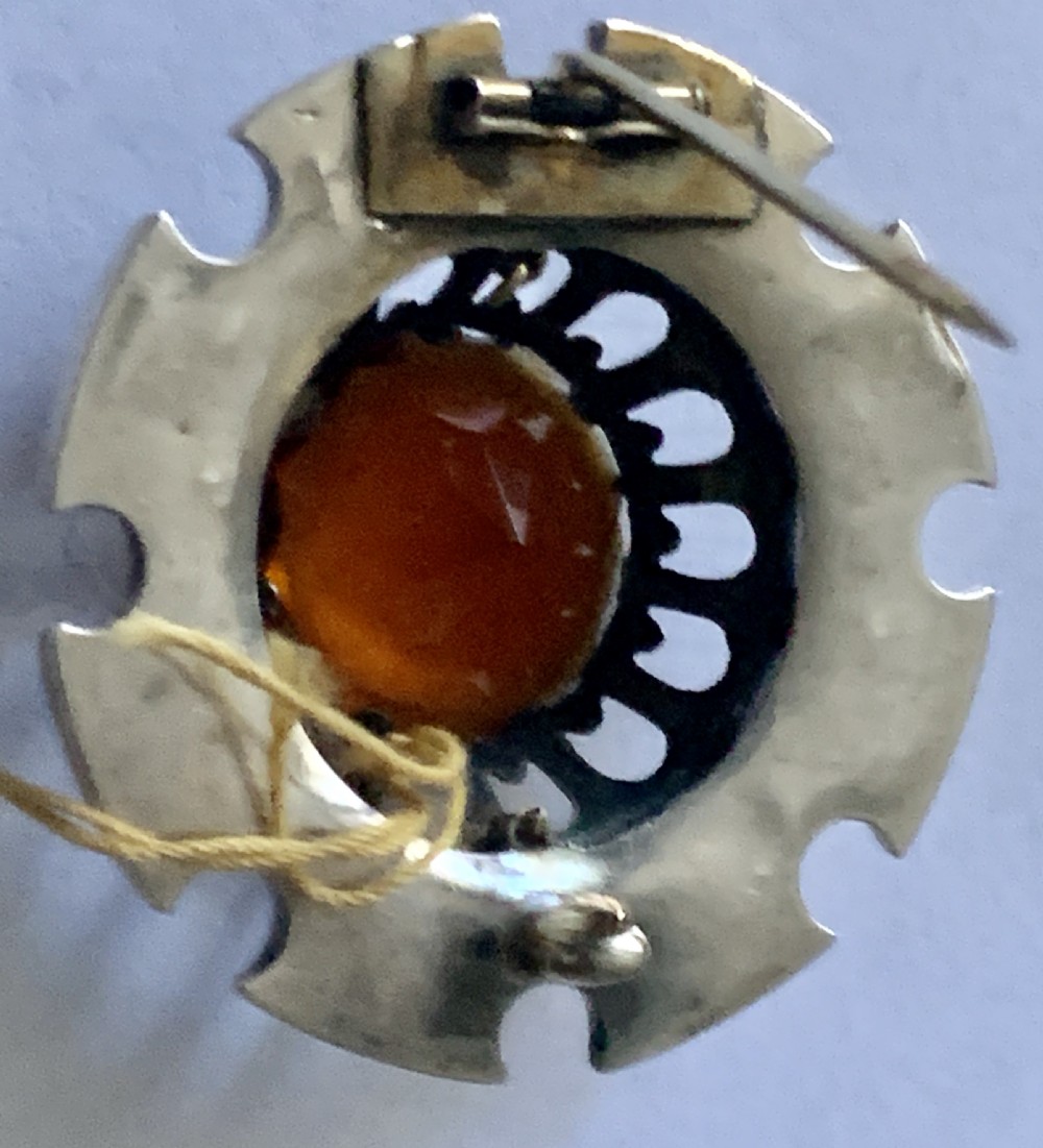 A circular Victorian silver Scottish brooch inlaid with red and green agate panels surrounding a large central faceted amber citrine stone. View V