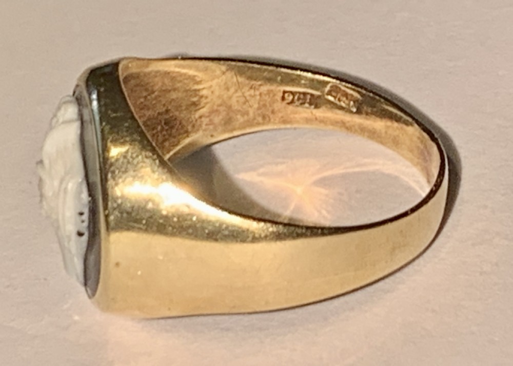 A Victorian 9ct yellow gold signet style ring set with an oval carved agate cameo depicting a white classical female profile against a dark background. View VI