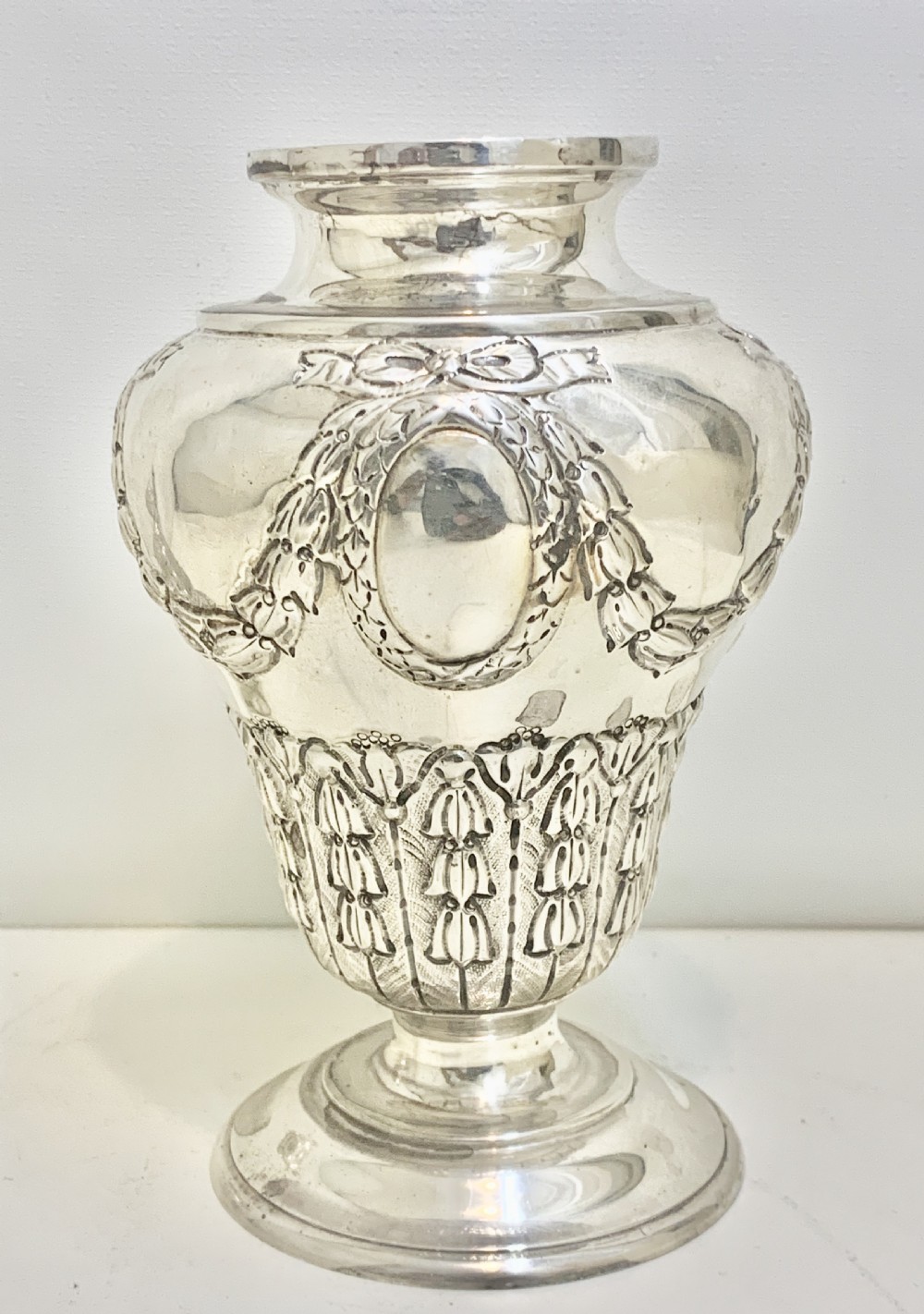 An urn-shaped Edwardian sterling silver sugar caster featuring chased ribbon bow swags and a pierced removable dome lid. View X