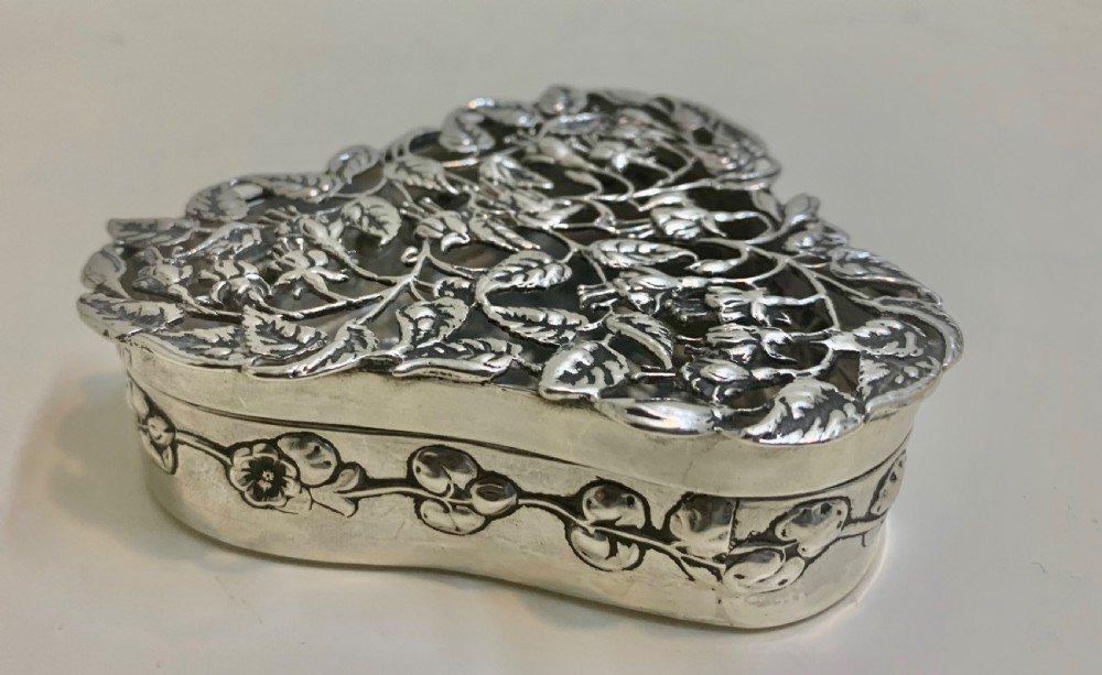 An Edwardian heart-shaped sterling silver trinket box featuring intricate pierced foliate openwork on the lid. View II