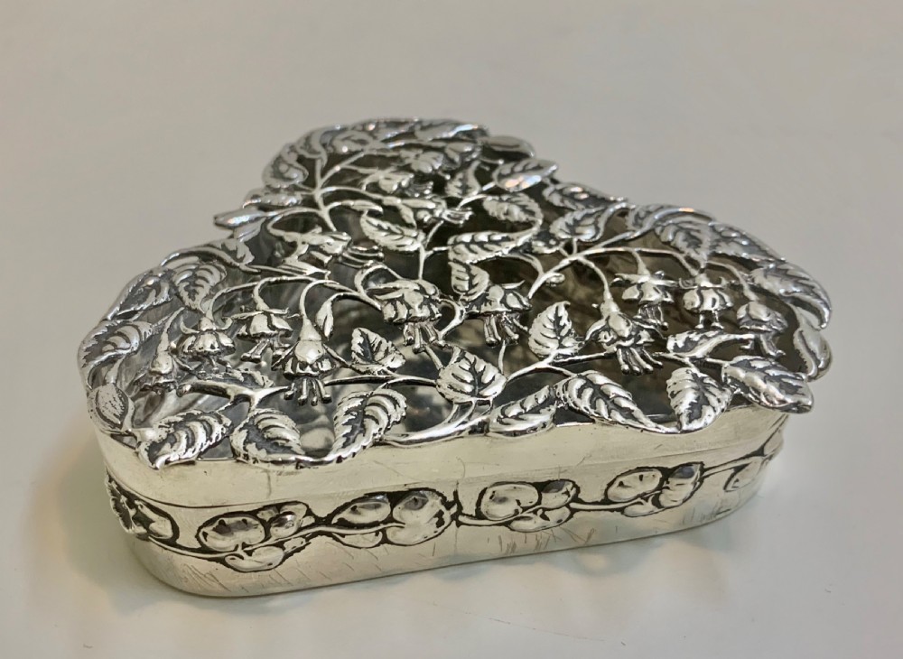 An Edwardian heart-shaped sterling silver trinket box featuring intricate pierced foliate openwork on the lid. View V