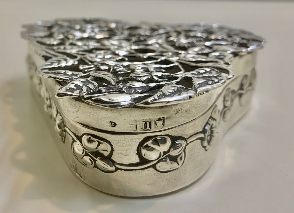 An Edwardian heart-shaped sterling silver trinket box featuring intricate pierced foliate openwork on the lid. View VII