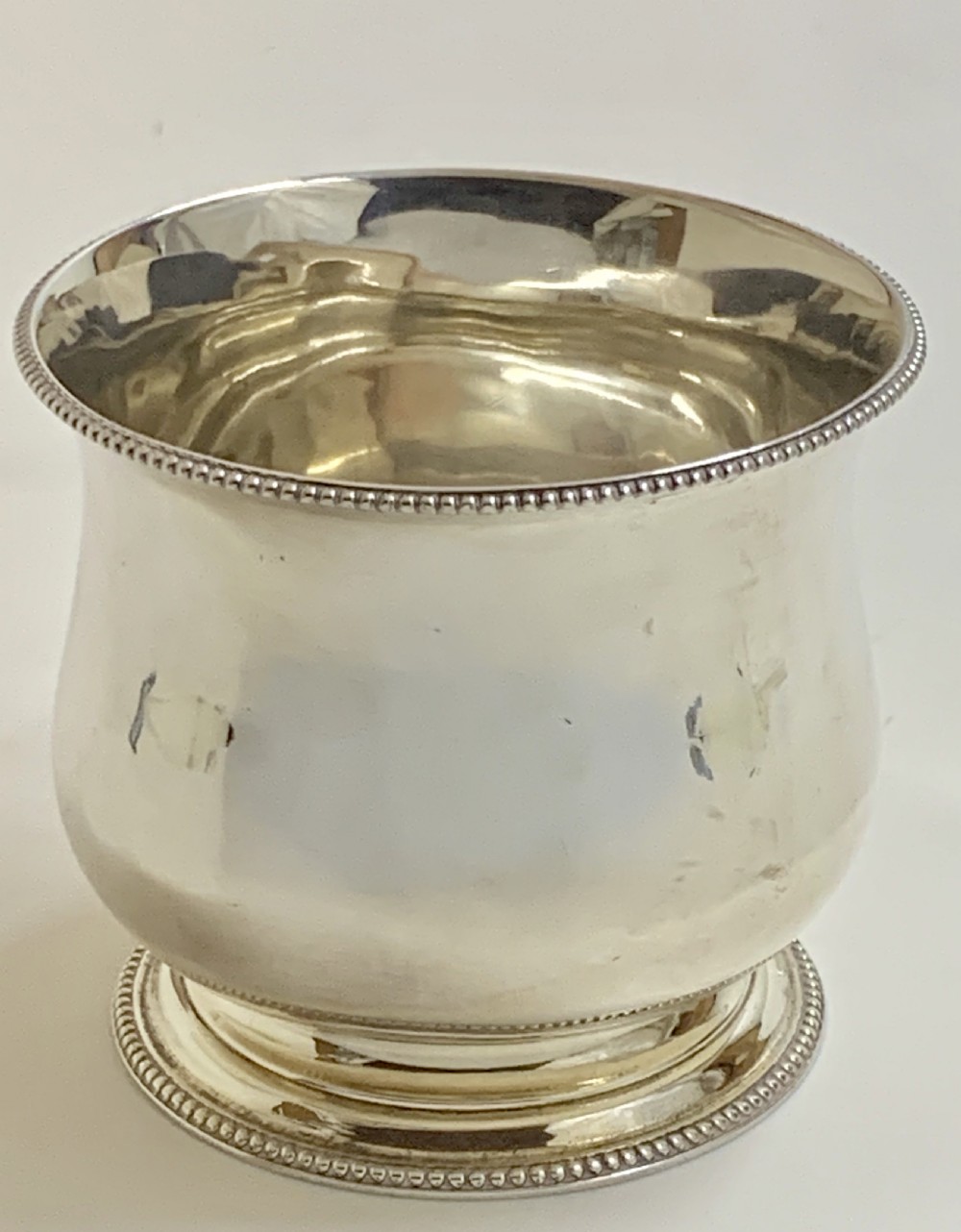 A sterling silver George III sugar bowl featuring a baluster form, beaded rim, and a circular pedestal foot.