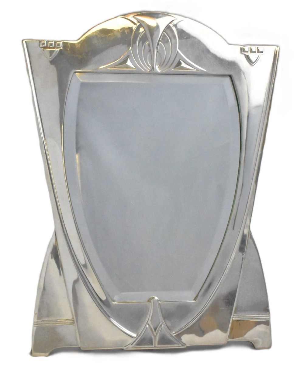 An antique silver-plated Art Nouveau easel-back mirror featuring geometric arch motifs and a bevelled shield-shaped glass frame.