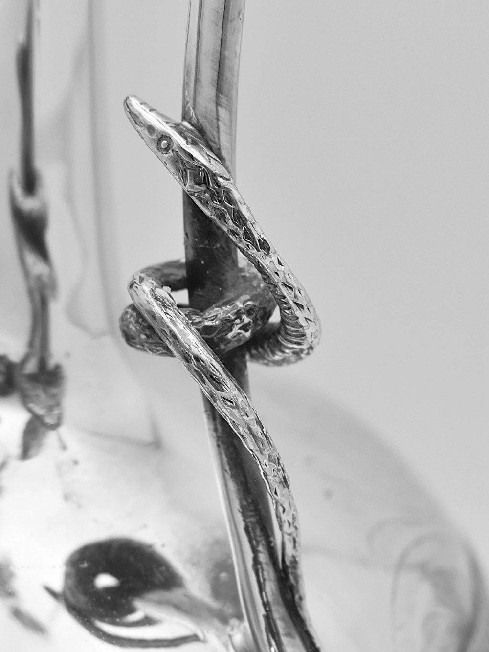 A pair of nineteenth-century clear crystal claret jugs featuring engraved silver mounts, tall necks, round stoppers, and silver handles shaped as entwined serpents. View III