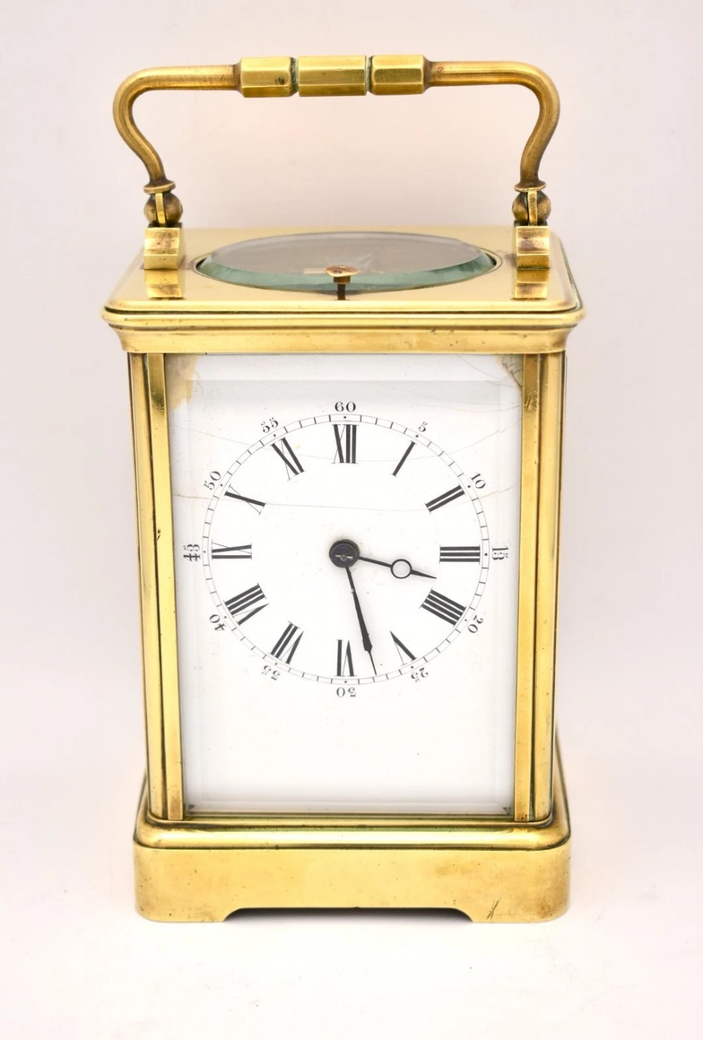 A Victorian brass carriage clock featuring a top handle, glass side panels, and a white enamel dial with Roman numerals.