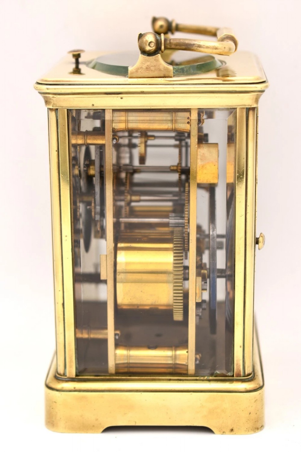 A Victorian brass carriage clock featuring a top handle, glass side panels, and a white enamel dial with Roman numerals. View IV