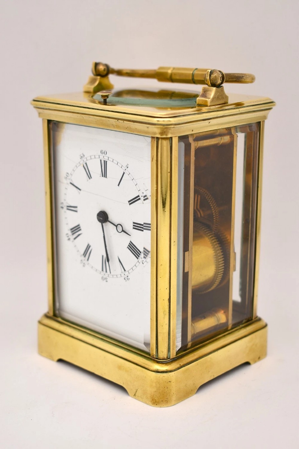 A Victorian brass carriage clock featuring a top handle, glass side panels, and a white enamel dial with Roman numerals. View V