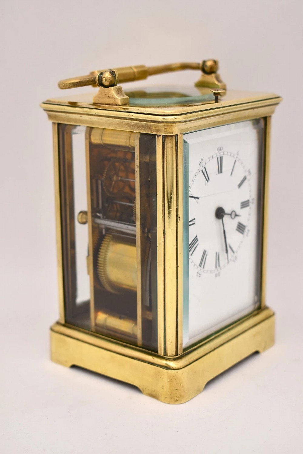 A Victorian brass carriage clock featuring a top handle, glass side panels, and a white enamel dial with Roman numerals. View VI