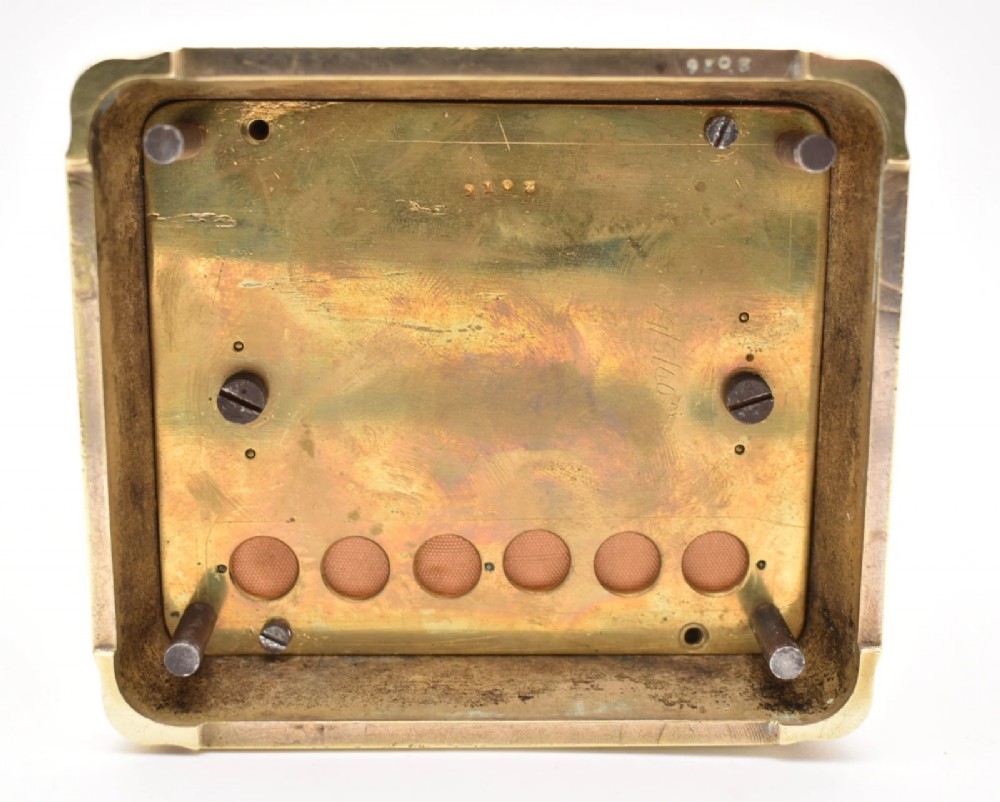 A rectangular polished brass French carriage clock featuring a doucine style case, top carrying handle, white enamel dial with Roman numerals, and glass side panels. View X