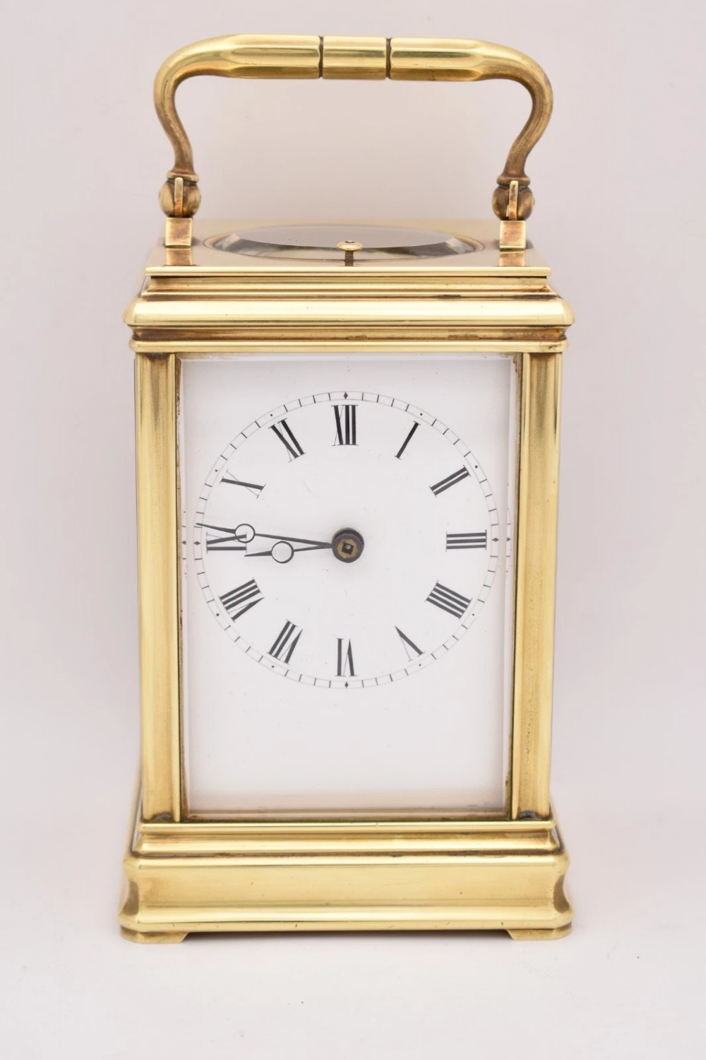 A late nineteenth-century French brass gorge case carriage clock featuring a white enamel dial with Roman numerals and a hinged top carrying handle.