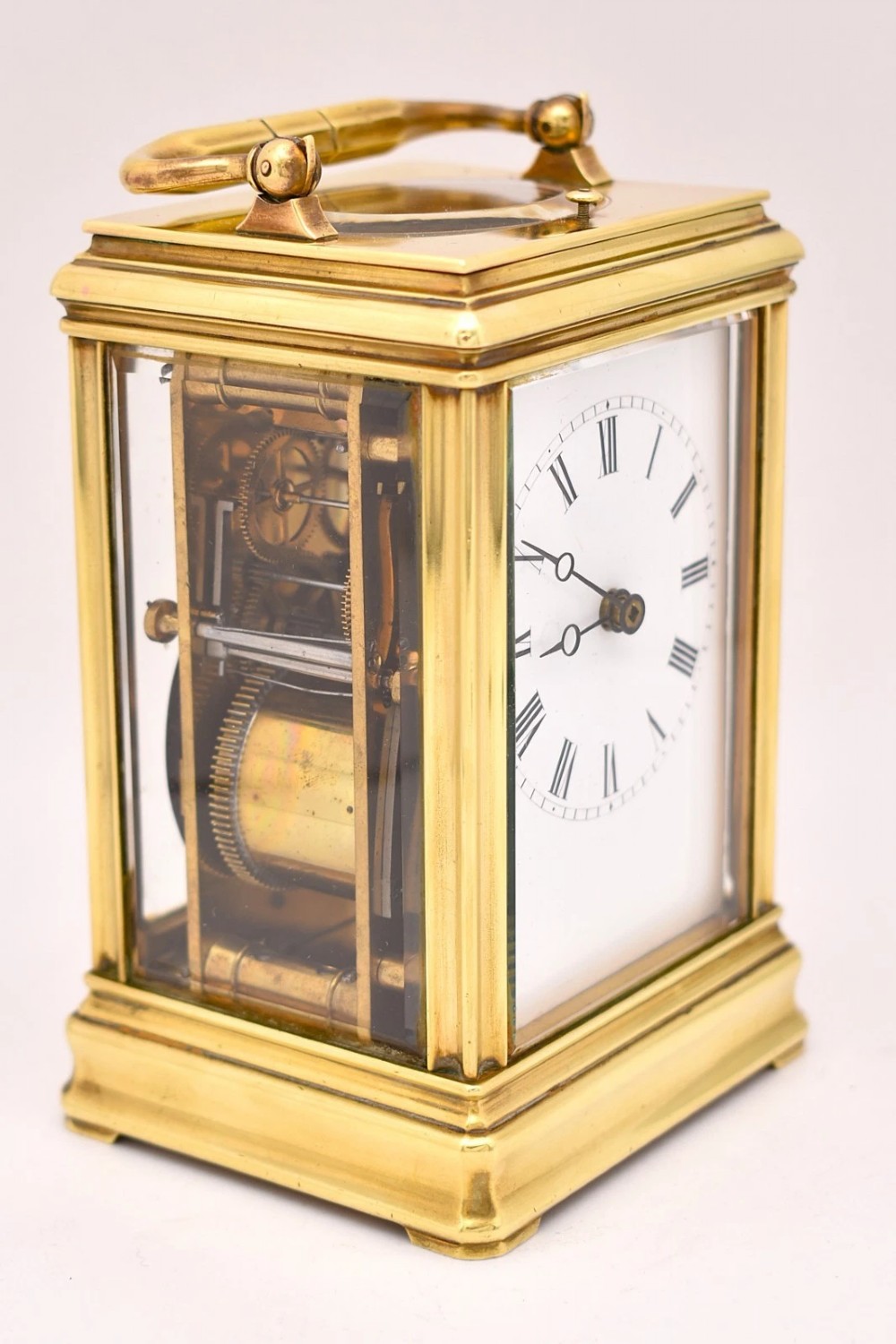 A late nineteenth-century French brass gorge case carriage clock featuring a white enamel dial with Roman numerals and a hinged top carrying handle. View VII