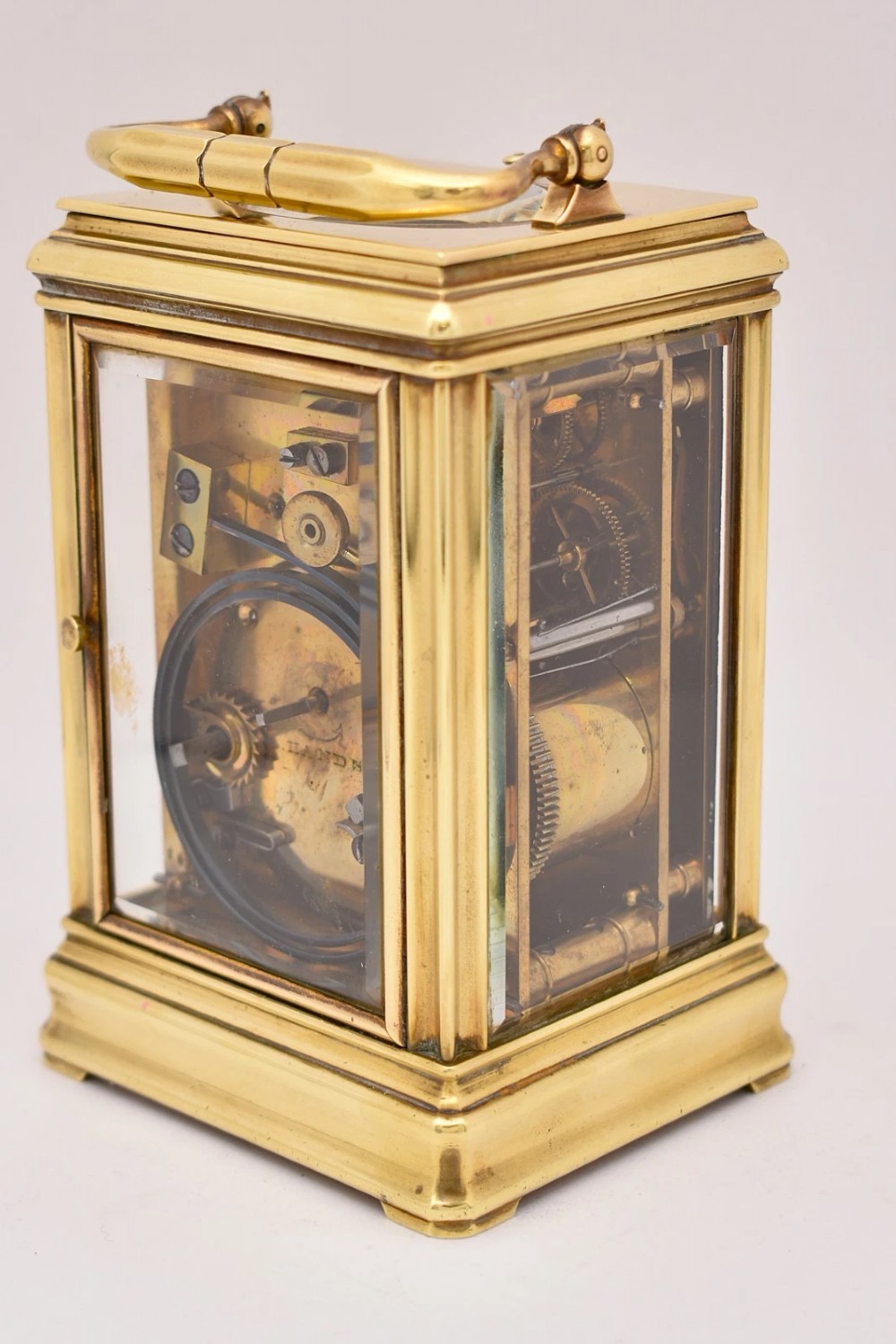 A late nineteenth-century French brass gorge case carriage clock featuring a white enamel dial with Roman numerals and a hinged top carrying handle. View VIII
