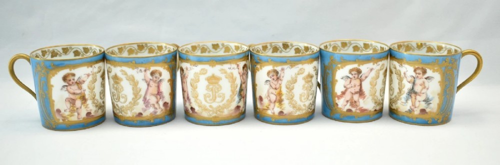 A six-piece set of white and sky-blue French porcelain demitasse cups and saucers decorated with gilded royal monograms, cherubs, and leaf borders. View II