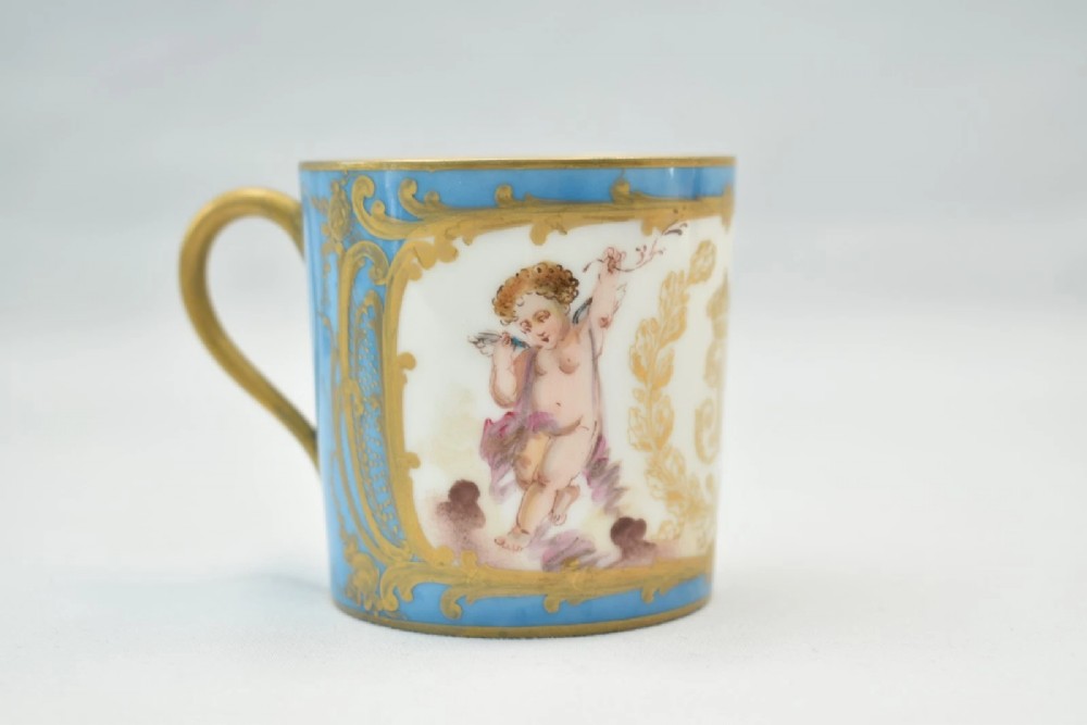 A six-piece set of white and sky-blue French porcelain demitasse cups and saucers decorated with gilded royal monograms, cherubs, and leaf borders. View IV