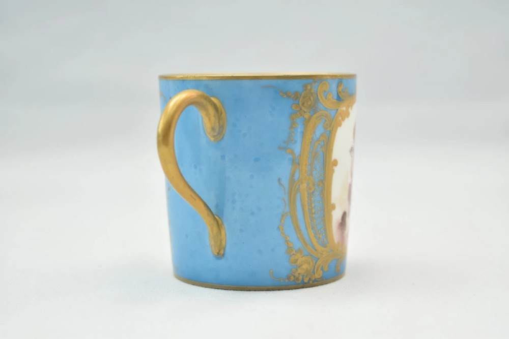 A six-piece set of white and sky-blue French porcelain demitasse cups and saucers decorated with gilded royal monograms, cherubs, and leaf borders. View V