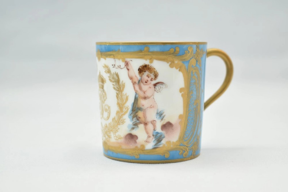 A six-piece set of white and sky-blue French porcelain demitasse cups and saucers decorated with gilded royal monograms, cherubs, and leaf borders. View VI
