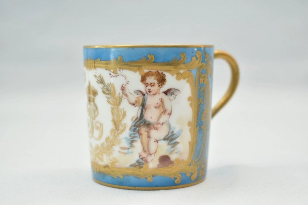 A six-piece set of white and sky-blue French porcelain demitasse cups and saucers decorated with gilded royal monograms, cherubs, and leaf borders. View VIII